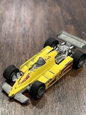 Petite voiture de course miniature jaune posée sur une surface en bois